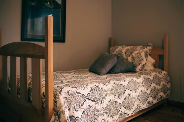 Charming bedroom interior featuring a wooden bed with decorative quilt and pillows. Intérieur de chambre charmant avec un lit en bois avec un édredon et des oreillers décorés.