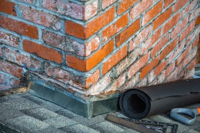 Detailed view of a brick chimney featuring construction tools and materials for repair. Vue détaillée d'une cheminée en brique avec des outils de construction et des matériaux de réparation.