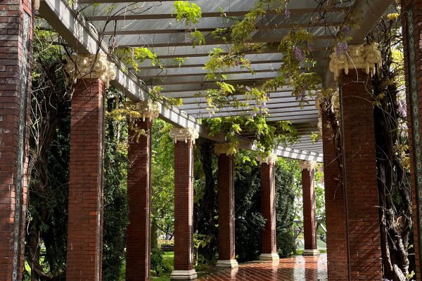 A scenic outdoor colonnade with vibrant brick and lush foliage on a sunny day. Un colonnade extérieur pittoresque avec des briques vibrants et un feuillage luxuriant par une journée ensoleillée.
