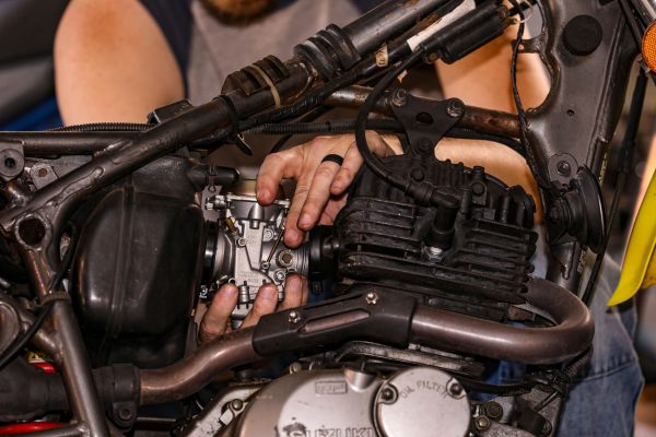 Mécanicien réparant avec expertise le moteur d'une moto, montrant son savoir-faire pratique.