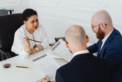 Three business professionals in discussion over a contract in a modern office setting. Trois professionnels en discussion sur un contrat dans un cadre de bureau moderne.
