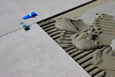 Close-up of wet cement and tile spacers during floor tile installation. Gros plan sur le ciment humide et les espaceurs de carrelage lors de l'installation de carrelage au sol.