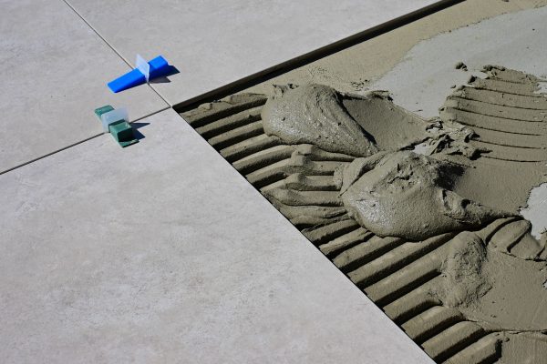 Close-up of wet cement and tile spacers during floor tile installation. Gros plan sur le ciment humide et les espaceurs de carrelage lors de l'installation de carrelage au sol.