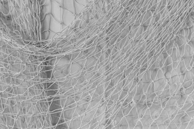 Gros plan détaillé de tissu entrelacé et filet de pêche montrant la texture et le motif en monochrome.