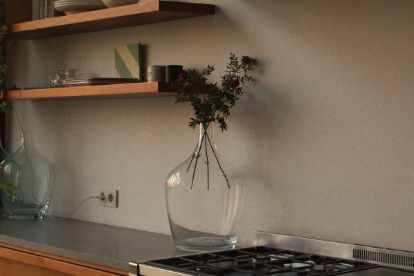 Cuisine élégante avec four en acier inoxydable, étagères en bois et décoration artistique.
