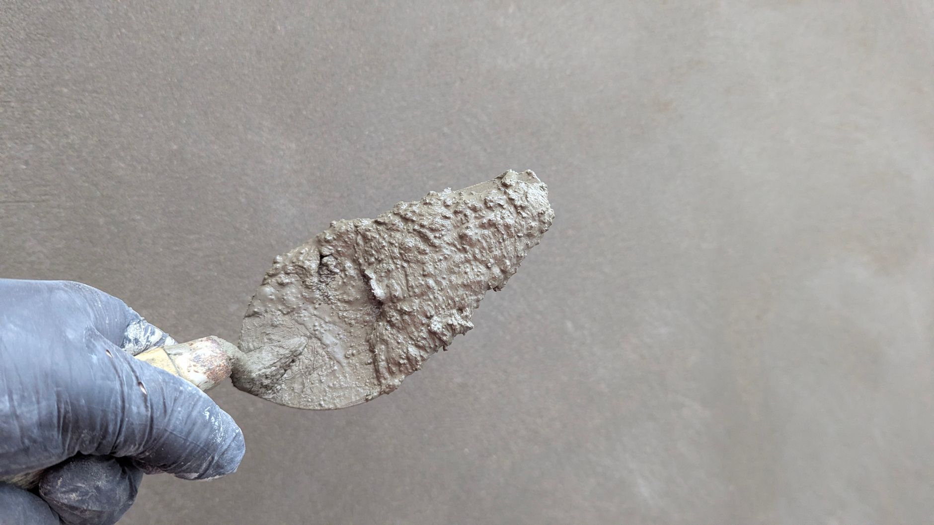 Main gantée lissant un enduit sur un mur