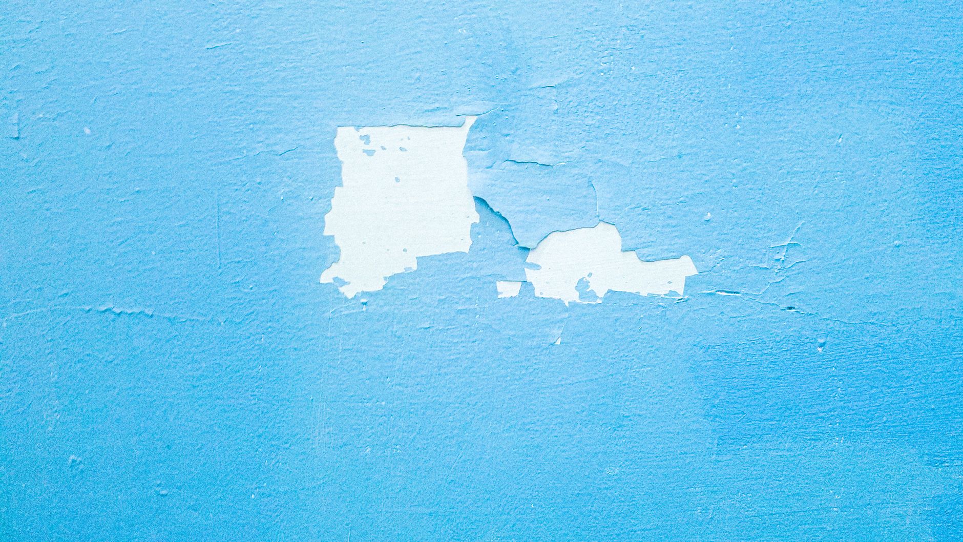 Mur bleu dont la peinture s’écaille et laisse voir les couches