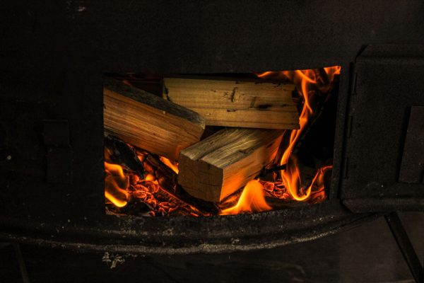 Bûches enflammées derrière la vitre d'un poêle à bois